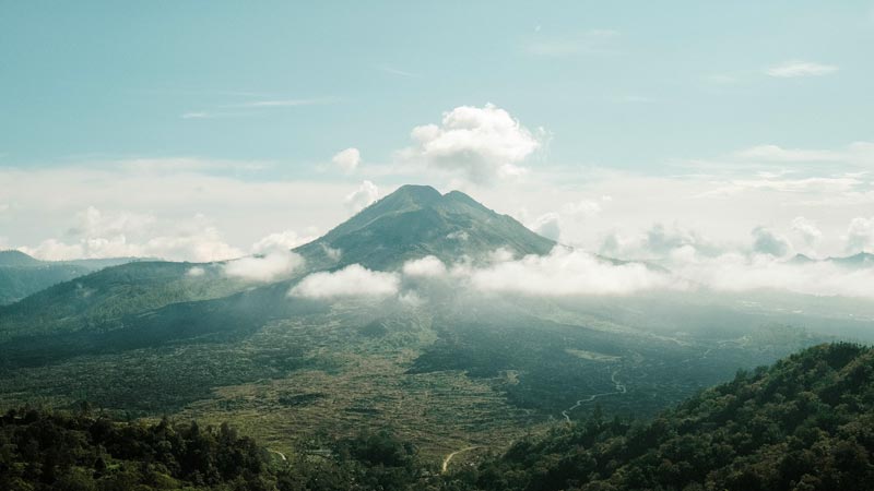 Mount Batur towering over Kintamani's landscape shrouded in clouds