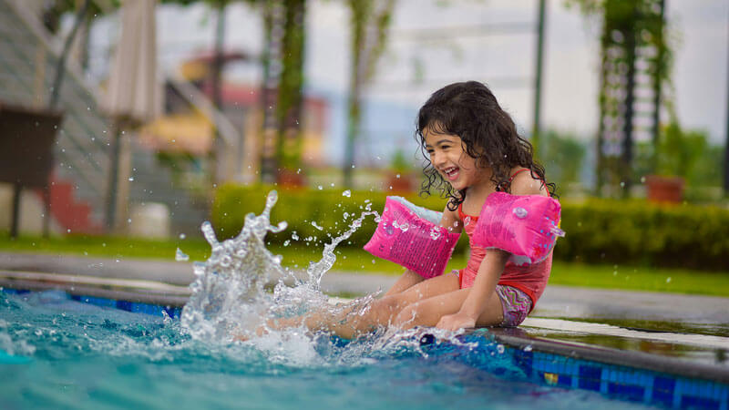 Cheerful girls playing in water with floats in swimming pool