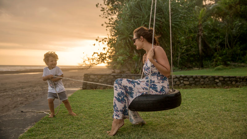 Mother and child enjoying time playing on Bali beach at dusk