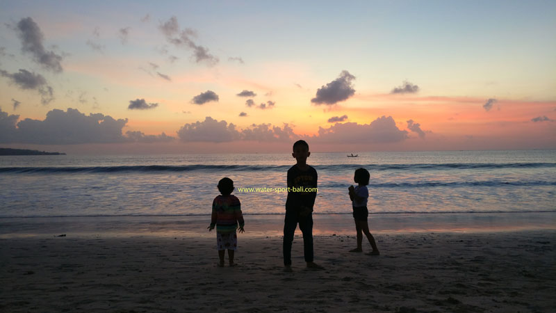 Silhouette of a family enjoying the sunset at Jimbaran Beach, Bali