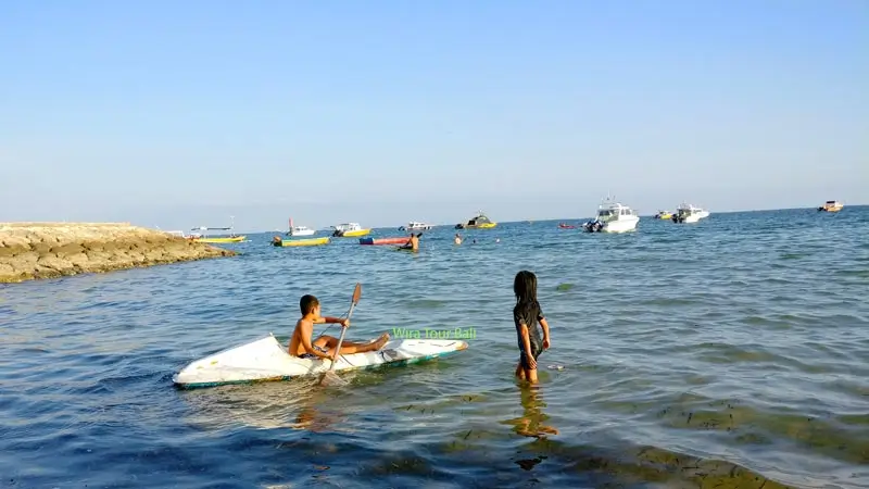 Children canoeing on the calm waters of Semawang Beach in Bali