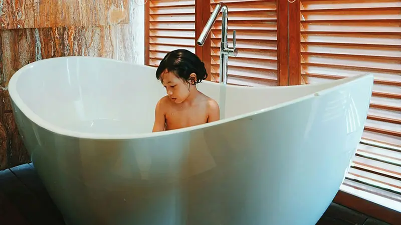 Child enjoying a leisurely bath in a spacious bathtub at a family-friendly Bali villa.