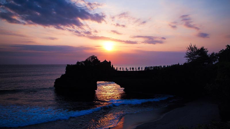 Sunset view at Tanah Lot Temple in Bali with silhouette of the temple and visitors