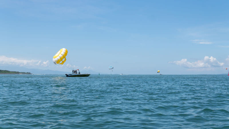 Parasailing adventure in Bali with a beach view as a backdrop, part of 5 Things You Need to Know About Bali Parasailing.