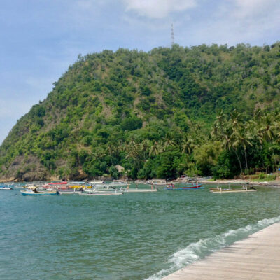 Scenic view of Labuhan Amuk Beach with traditional boats and lush greenery in Karangasem, Bali