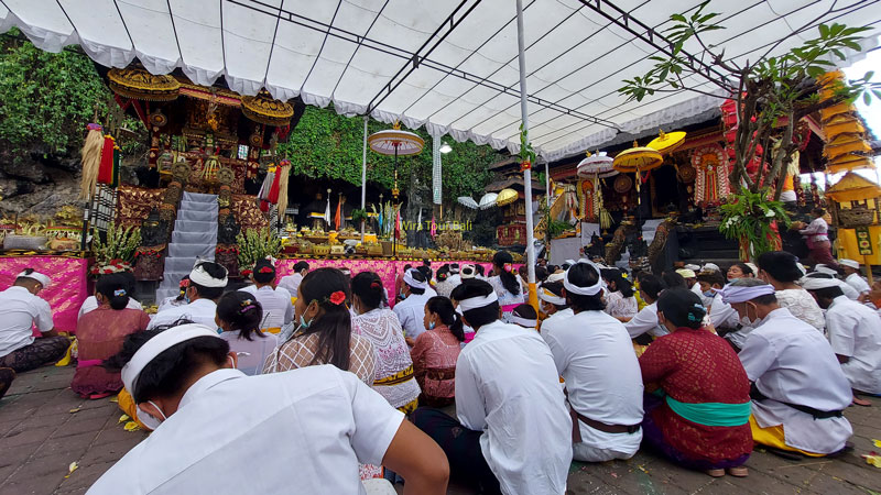 Balinese worshippers in traditional attire at Goa Lawah Temple ceremony