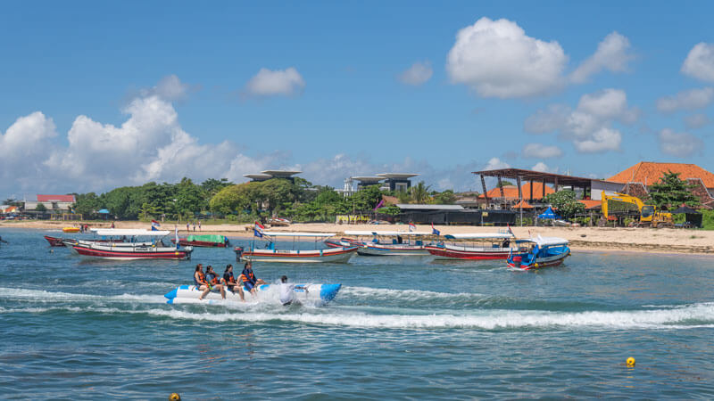 Group of friends enjoying a banana boat ride at Tanjung Benoa, with safety vests and an instructor guiding. One of the best Bali water sports suitable for non-swimmers