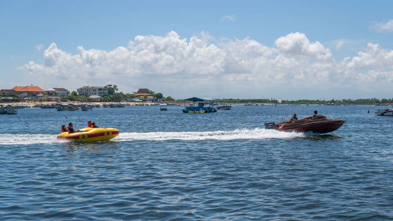 Exciting rolling doughnut water ride at Bali Beach with tourists enjoying, towed by a speedboat.