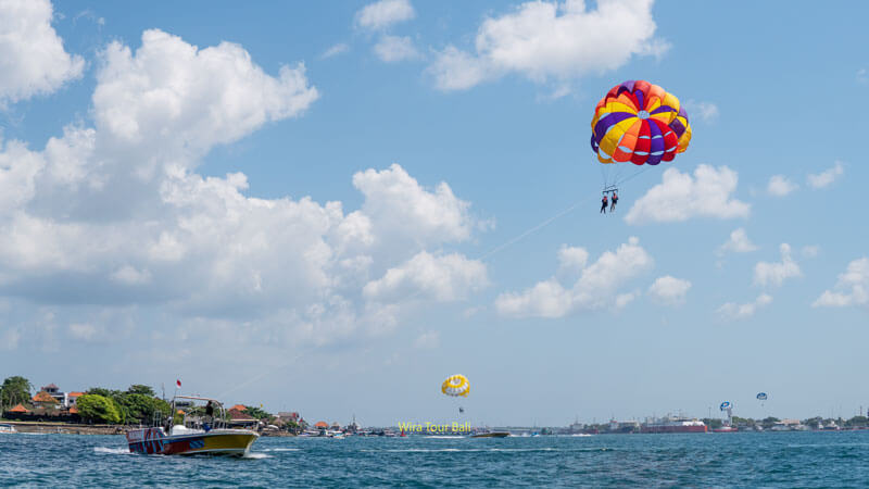 Parasailing in the clear blue sky over Tanjung Benoa. One of the best Bali water sports suitable for non-swimmers