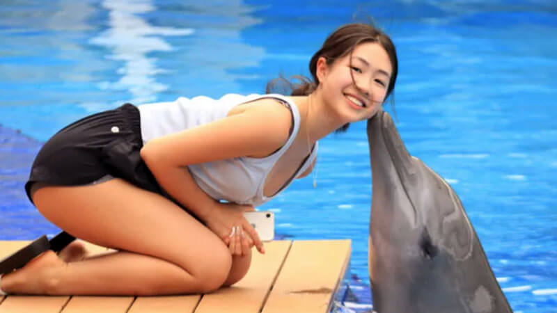 A visitor posing for a unique 'Dolphin Kiss' photo during the Explorer Program