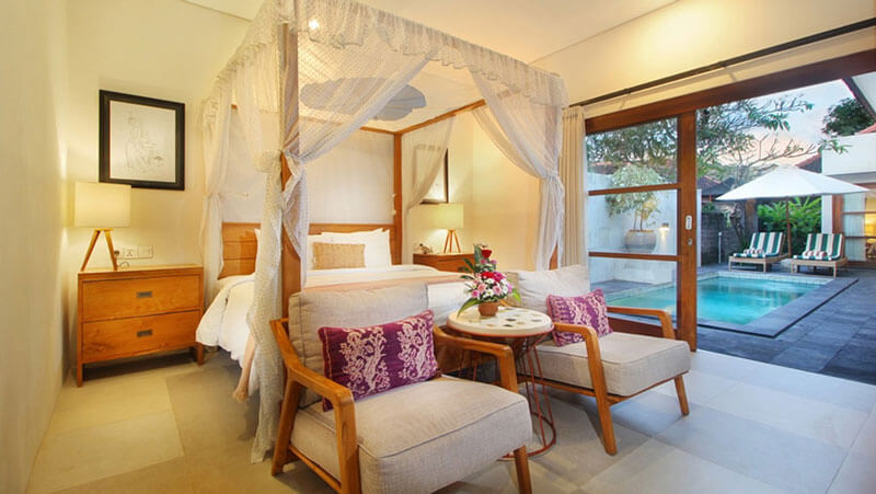 Elegant room with a canopy bed overlooking a private pool at AlamKulKul Boutique Resort, Bali.