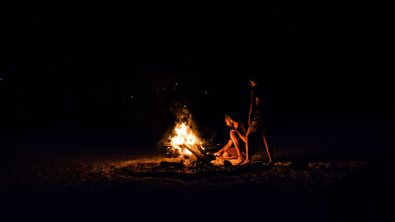 Travelers enjoying a beach bonfire at night in Gili Trawangan.