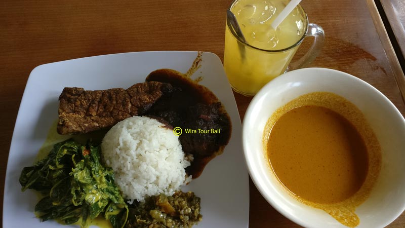 Delicious Padang cuisine from Rumah Makan Rindu Rasa, featuring beef rendang, vegetable dishes, and a bowl of rich curry with a refreshing drink.