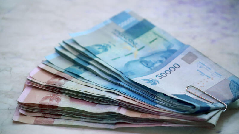 Stack of Indonesian Rupiah bills on a marble surface.