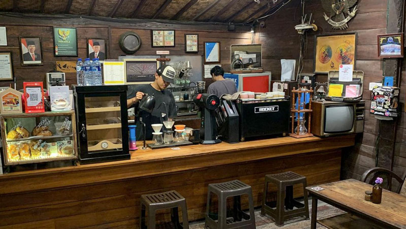 Baristas at work behind the counter of Karakter Kopi Bali with an array of coffee equipment and rustic decor