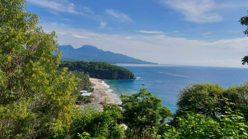 Scenic view of Virgin Beach with its pristine white sands framed by lush greenery and a clear blue sea in Karangasem, one of 5 Hidden Beaches in East Bali