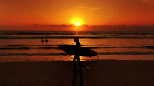 Sunset view at Legian Beach, Bali with surfers in the distance