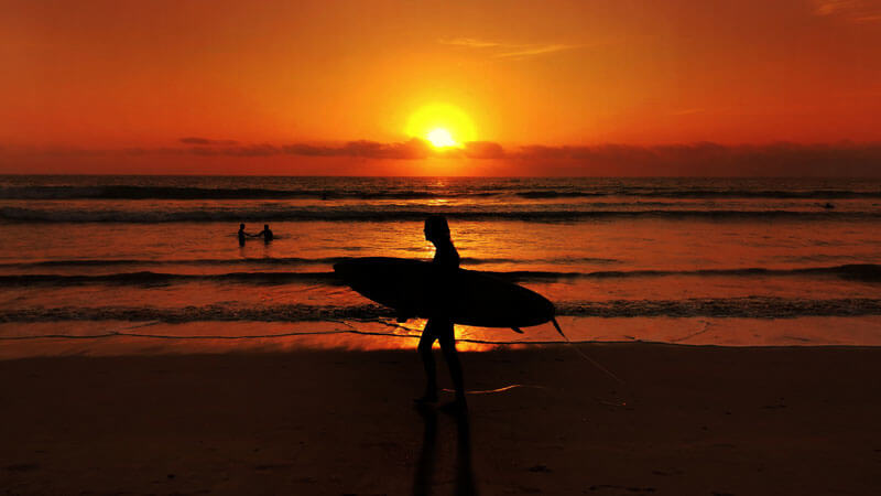 Sunset view at Legian Beach, Bali with surfers in the distance