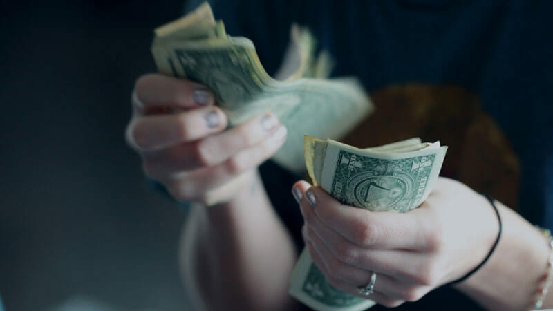 Person counting dollar bills for budget travel