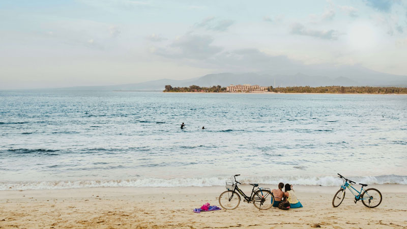Relaxed beach scene with bicycles and swimmers