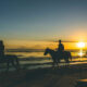 Horseback riding on Gili Trawangan beach at sunset with Mount Agung in the distance.