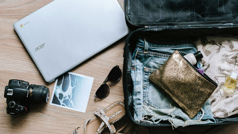 Open suitcase with travel essentials including camera, sunglasses, and casual wear for a Gili Trawangan trip.