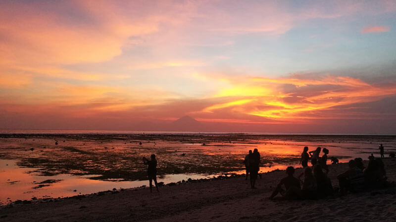 Sunset view at Lombok Island with tourist playing on the beach