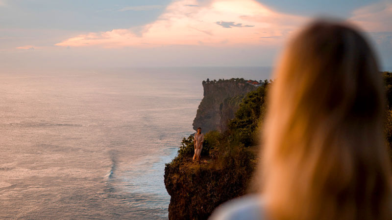 Visitor enjoying the breathtaking sunset view at Uluwatu Temple, Bali's renowned sunset spot.