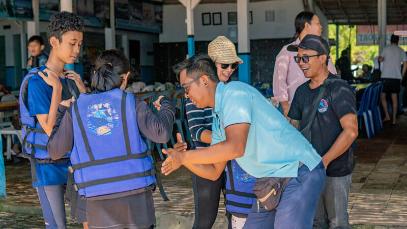 Instructor fitting a life jacket on a young parasailer for safety in Bali