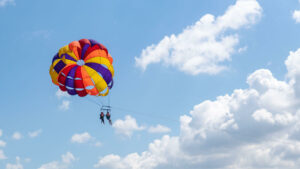 Tourists parasailing against a backdrop of bright blue sky and fluffy clouds in Bali.