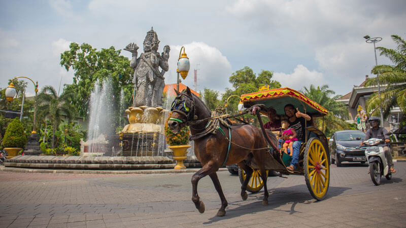 Traditional horse-drawn carriage in front of Bajra Sandhi Monument in Denpasar, offering a cultural transport option for tourists.