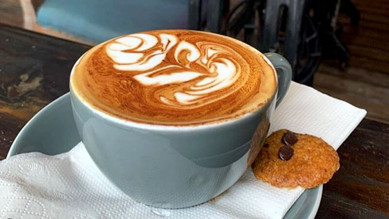 Artful latte with cookie at The Dusty Cafe Seminyak.