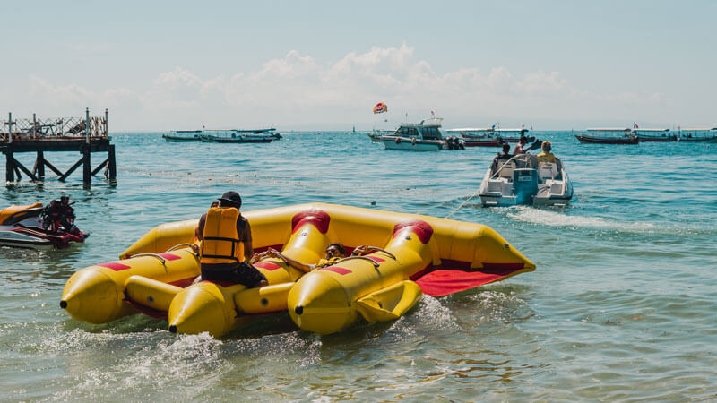 Inflatable Flying Fish Ride in the Calm Waters of Tanjung Benoa with Parasailing in the Background