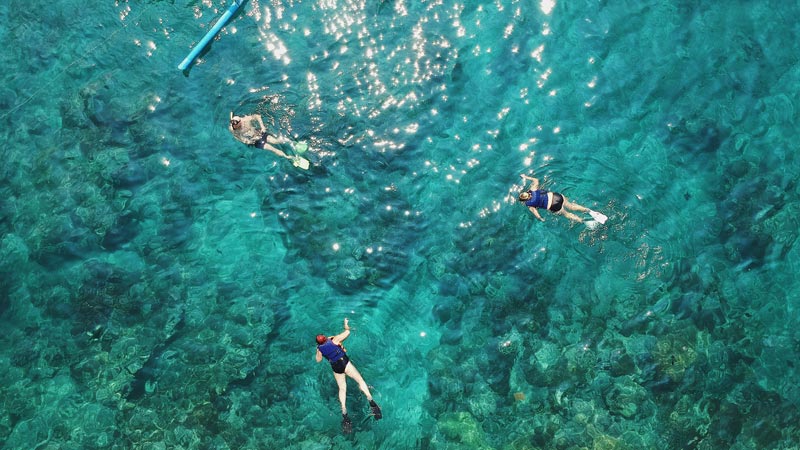 Snorkelers exploring the vibrant underwater world of Blue Lagoon Beach, with clear, shimmering waters revealing rich coral reefs one of 5 Hidden Beaches in East Bali