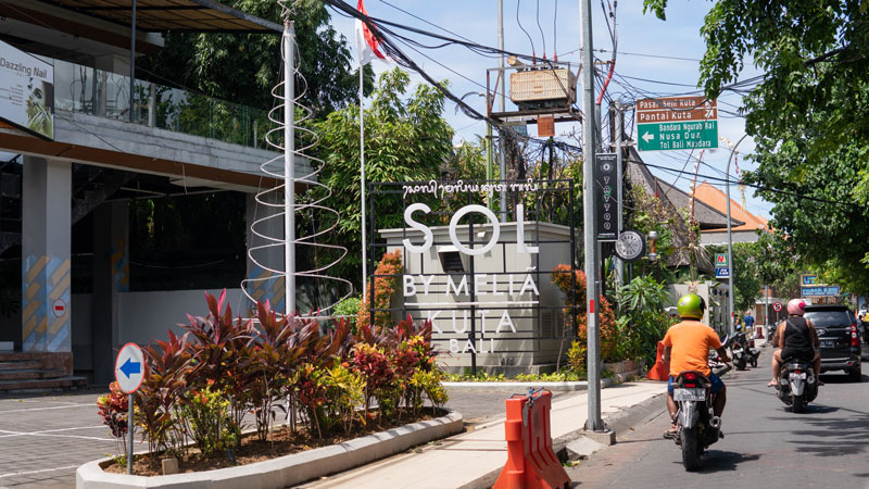 Busy Bali street with directional signage to Kuta Beach, showcasing typical transportation flow.