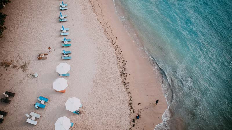 Aerial view of Karang Sanur Beach with beach umbrellas arranged on the edge of the blue sea