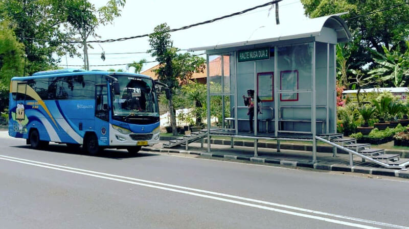 Trans Sarbagita bus passing by a bus stop in Bali, offering budget-friendly travel options.