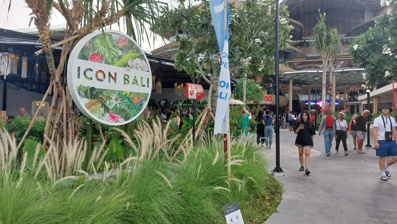 Icon Bali signage surrounded by greenery, with people walking through Jalan Danau Tamblingan.
