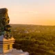 Aerial view of the Garuda Wisnu Kencana statue at sunset, overlooking lush green hills in Bali, Indonesia. © GWK Bali.