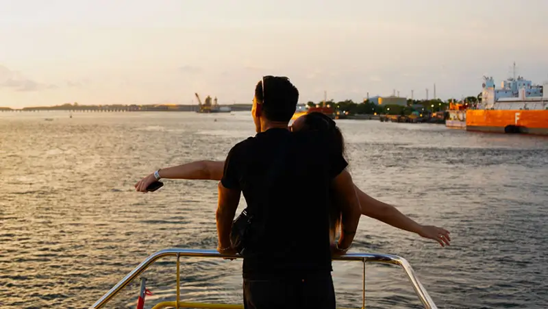 A couple enjoying the ocean breeze on a romantic sunset cruise.
