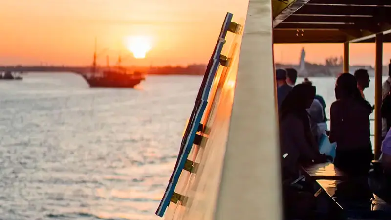 Guests enjoying a Bali Bounty Sunset Dinner Cruise with ocean views and a golden sunset in the background.