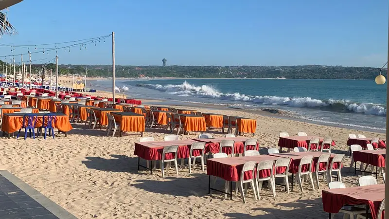 Daytime view of beachfront dining tables at Jimbaran Beach Bali.