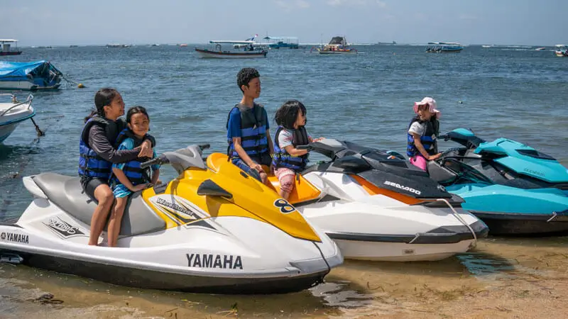 Families with kids wearing life jackets prepare for a beginner Jet Ski ride at Tanjung Benoa, Bali.