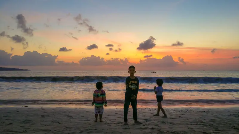 Children enjoying sunset views at Jimbaran Beach Bali. © Wira Tour