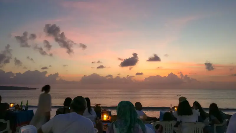 Group of friends enjoying seafood dinner at sunset on Jimbaran Beach Bali. © Wira Tour