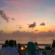 Tourists enjoy a seafood dinner at Jimbaran Beach Bali with sunset views and gentle waves in the background. © Wira Tour