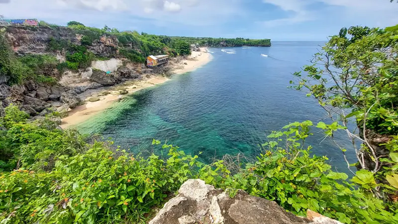 Panoramic view of Balangan Beach Bali from the cliffside, showing the yellow warung and turquoise reef bay.