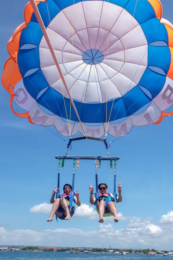 Two happy guests parasailing calmly over Tanjung Benoa, Bali