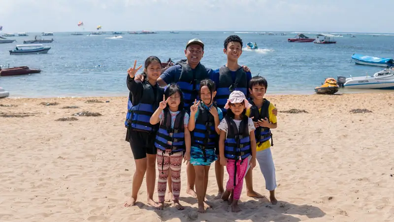 Family with kids in life vests on Tanjung Benoa Beach before water sports
