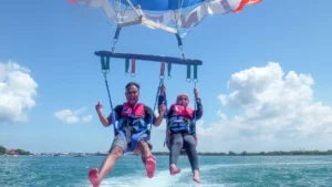 Smiling couple enjoying tandem parasailing over calm waters in Tanjung Benoa, Bali